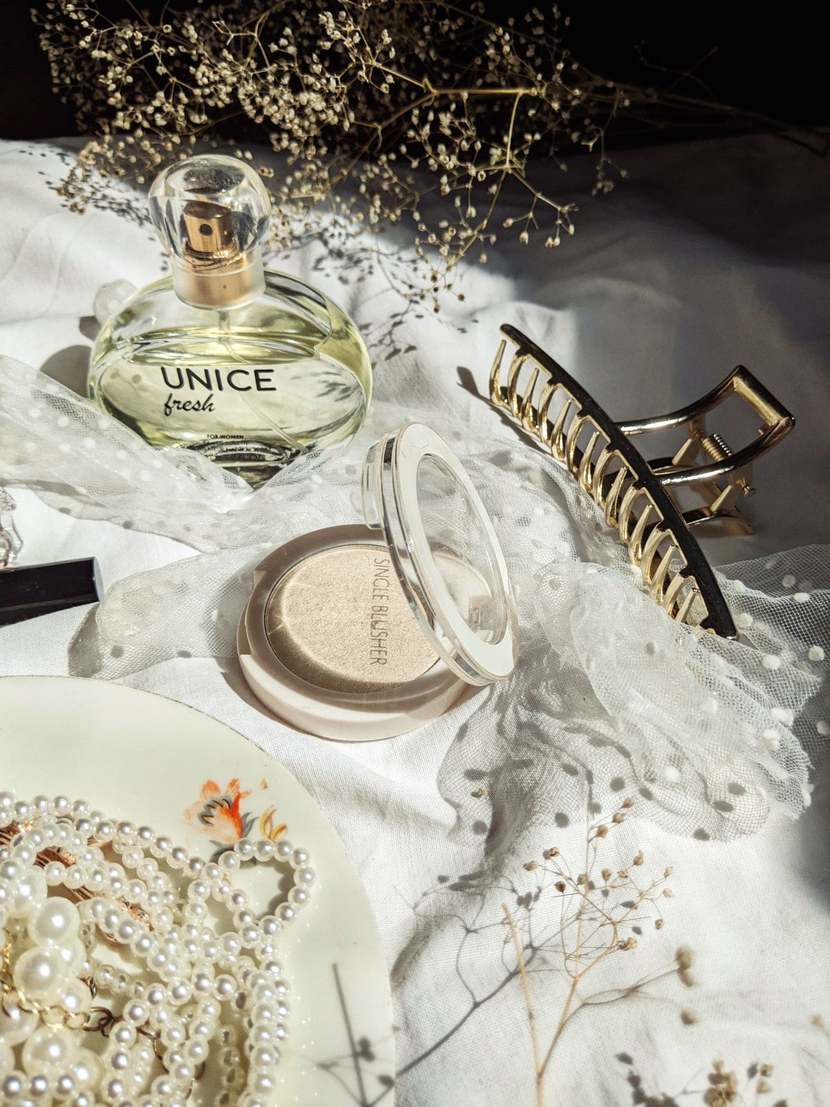 A flat-lay showing a clear bottle of jewelry seal/protective coat alongside hypoallergenic pieces.