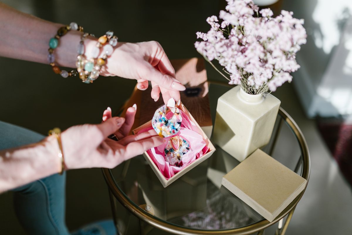 Setting rings and hoop earrings inside a structured jewellery pouch on a vanity.
