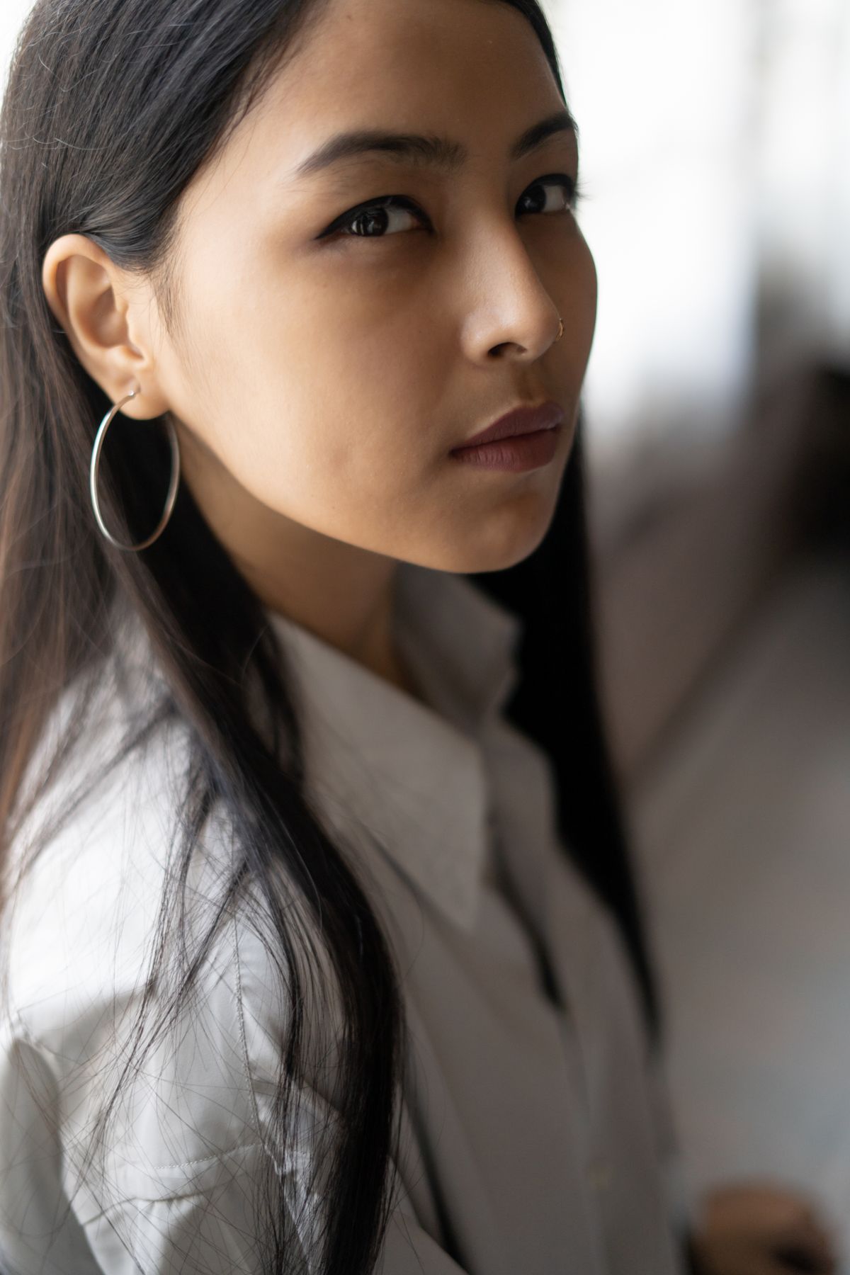 A classic white shirt accessorized with medium gold hoops and a structured wrist cuff.