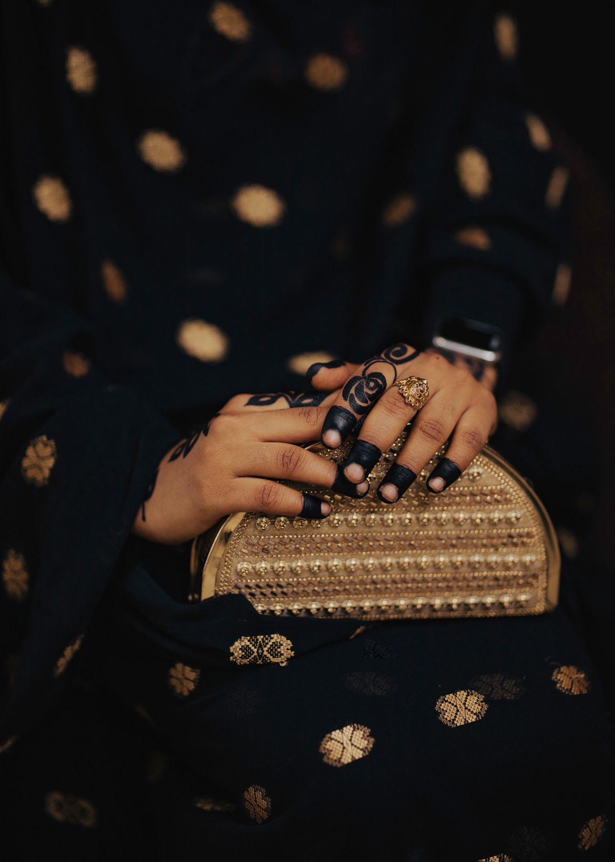 A close-up of a hand holding an evening clutch, showcasing a sparkling cocktail ring.