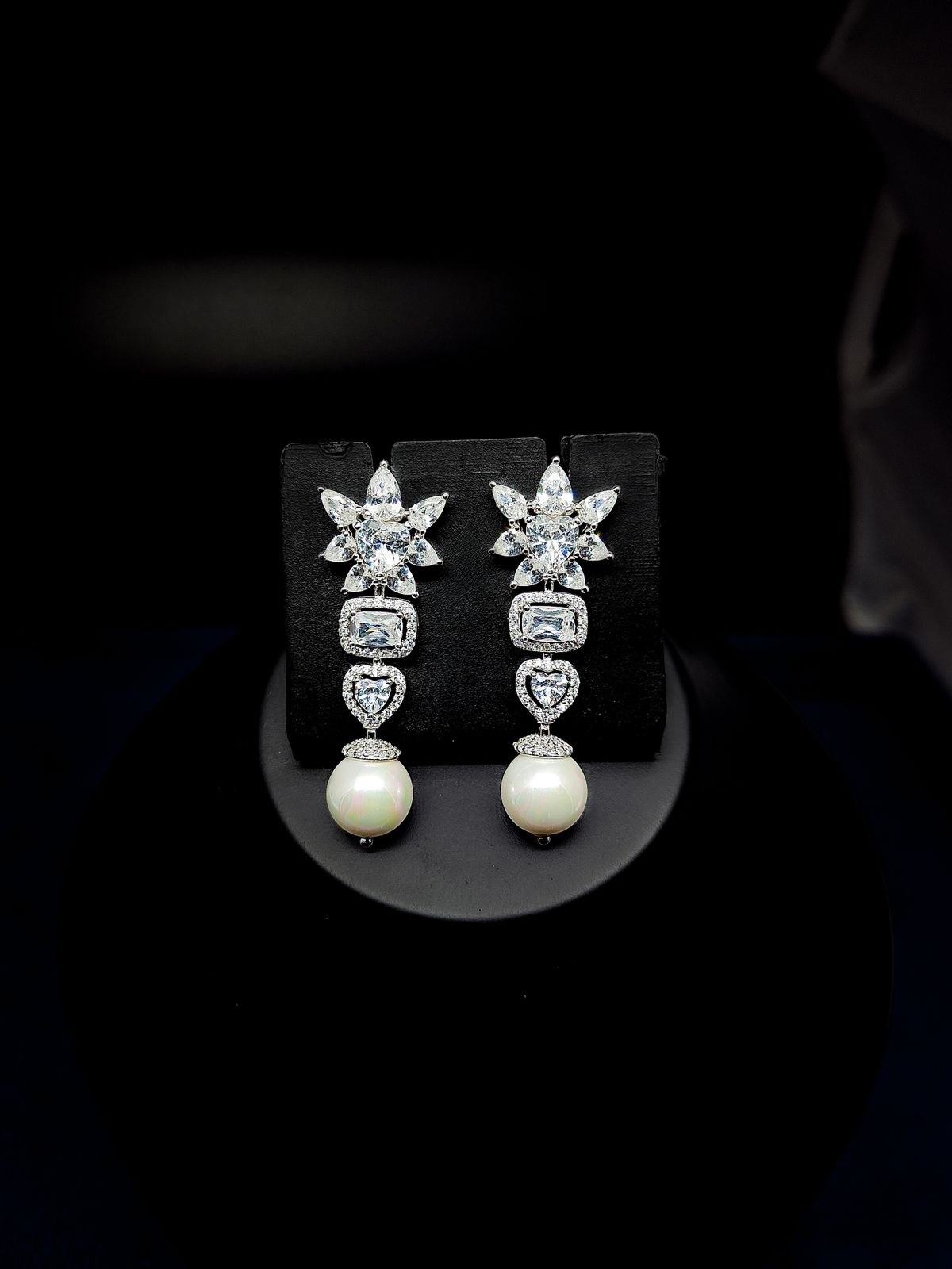 Statement drop earrings frame your face under warm gala lighting.