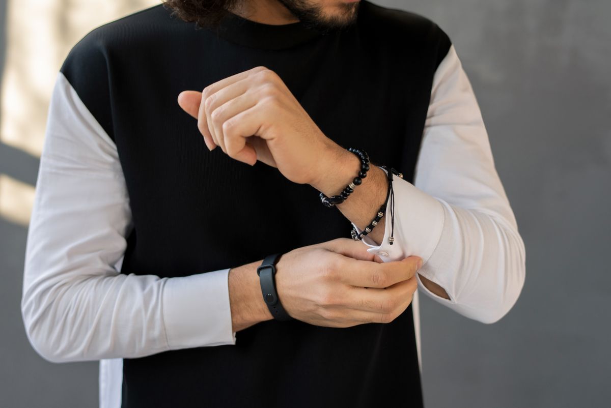 Rolled button-down sleeves free up wrist space for a layered chain stack.