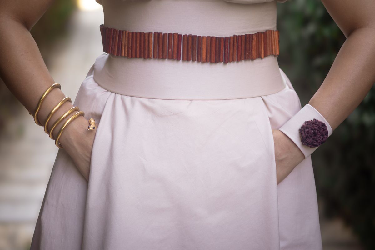 Wearing a structured cuff over a fitted knit sleeve creates a sleek, high-fashion accent.